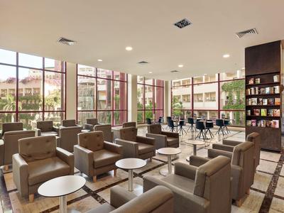 Moderne Hotellobby mit Sitzgruppen und großen Fenstern, die Tageslicht hereinlassen.