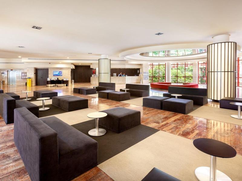 Area lounge dell'hotel moderna e luminosa con divani neri e pavimento in legno.