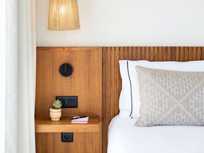 Chambre moderne avec panneau mural en bois, lampe suspendue et coussin décoratif.