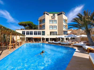 Hôtel moderne avec grande piscine et chaises longues sous un ciel bleu.