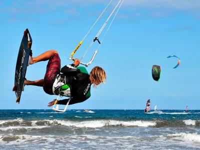 Kitesurfer che salta sulle onde sotto un cielo sereno sulla spiaggia.