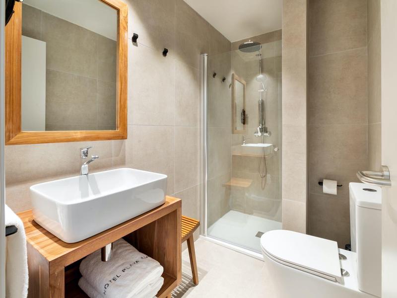 Salle de bain moderne avec douche, lavabo rectangulaire et mobilier en bois.