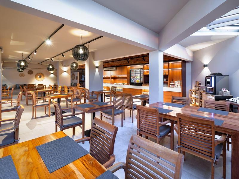 Restaurant moderne avec tables et chaises en bois, éclairage chaleureux et espace ouvert.