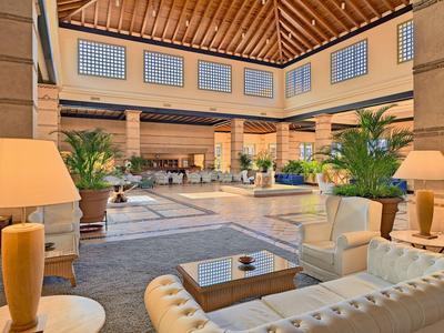 Luminoso vestíbulo de hotel con sofás cómodos, plantas y techo de vigas de madera.