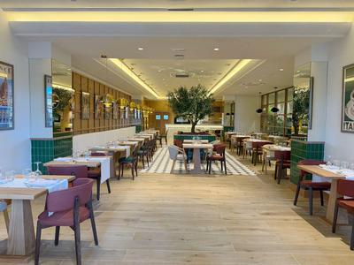 Restaurant lumineux et moderne avec tables, chaises et plantes pour les clients de l'hôtel.