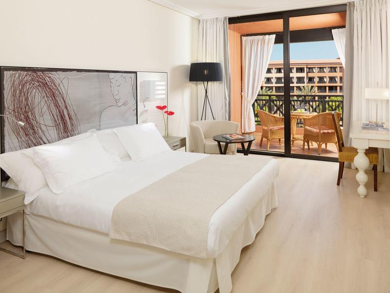 Moderne hotelkamer met groot tweepersoonsbed en balkon met uitzicht op de tuin.