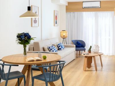 Modern eingerichtetes Wohnzimmer mit Holzfußboden, Essbereich und hellen Vorhängen.
