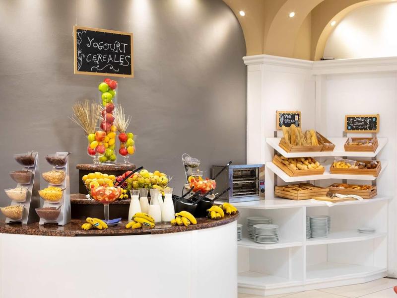 Buffet con frutas frescas, bollería y postres en una zona luminosa del hotel.