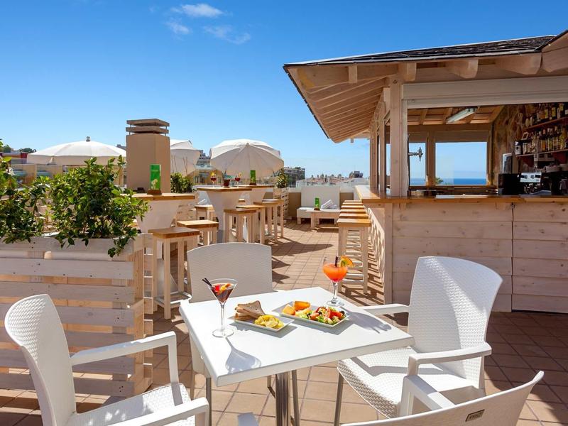 Terraza soleada con áreas de asientos y bar en un resort vacacional.