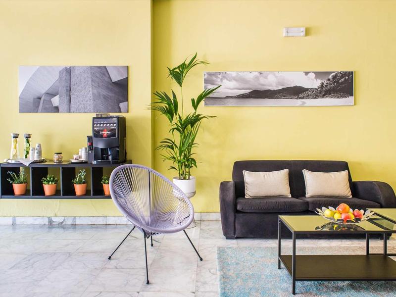 Modern living room with yellow wall, gray sofa, and plants.