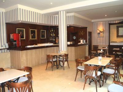 Gemütlicher Gastraum mit Holztischen, Stühlen, gestreiften Wänden und beleuchtetem Barbereich.