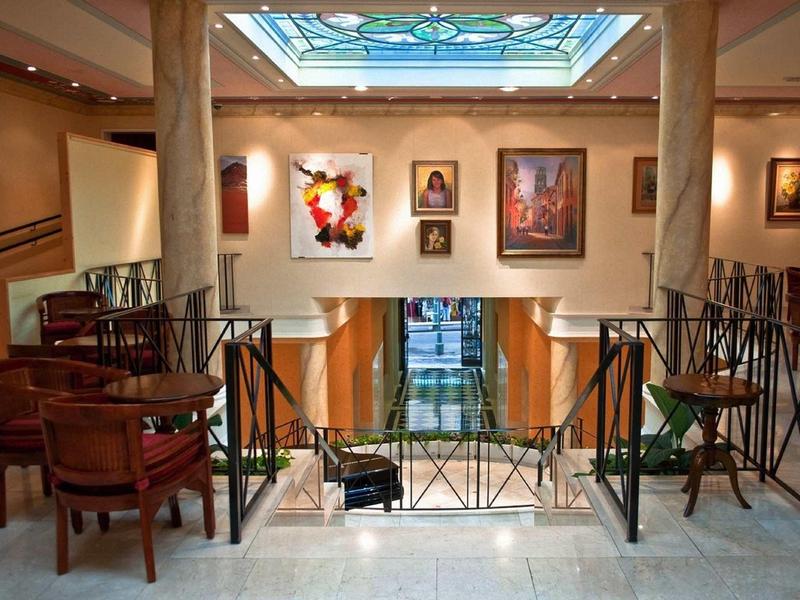 Gemütlicher Innenraum mit holzstühlen, gemälden an den wänden und bunter glasdecke.