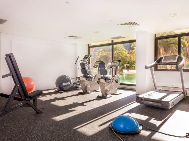 Palestra luminosa con attrezzature cardio e grande finestra con vista sul verde.