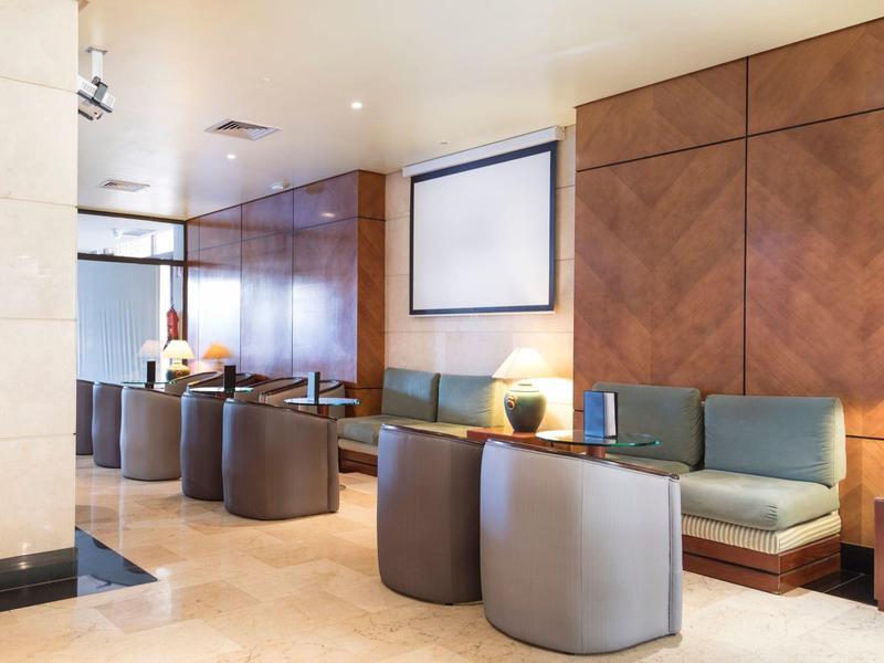 Area lounge moderna dell'hotel con pareti in legno e comode poltrone grigie.