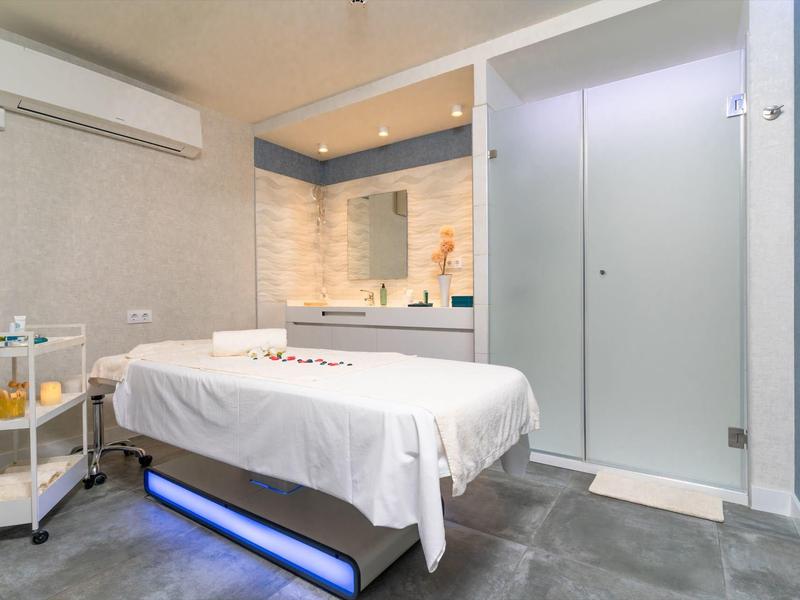 Modernes Behandlungszimmer mit Massagebank, stilvoller Beleuchtung und minimalistischer Einrichtung.