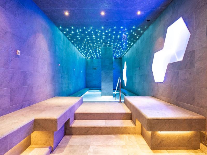 Moderner, atmosphärisch beleuchteter Spa-Raum mit Betonbänken und Treppen