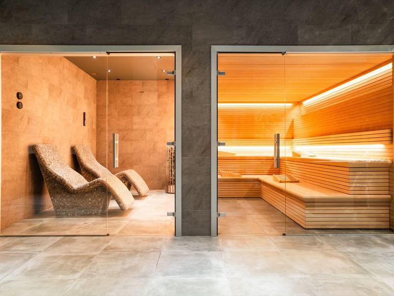 Moderner Wellnessbereich mit Liegen und Sauna in warmen, einladenden Farben.