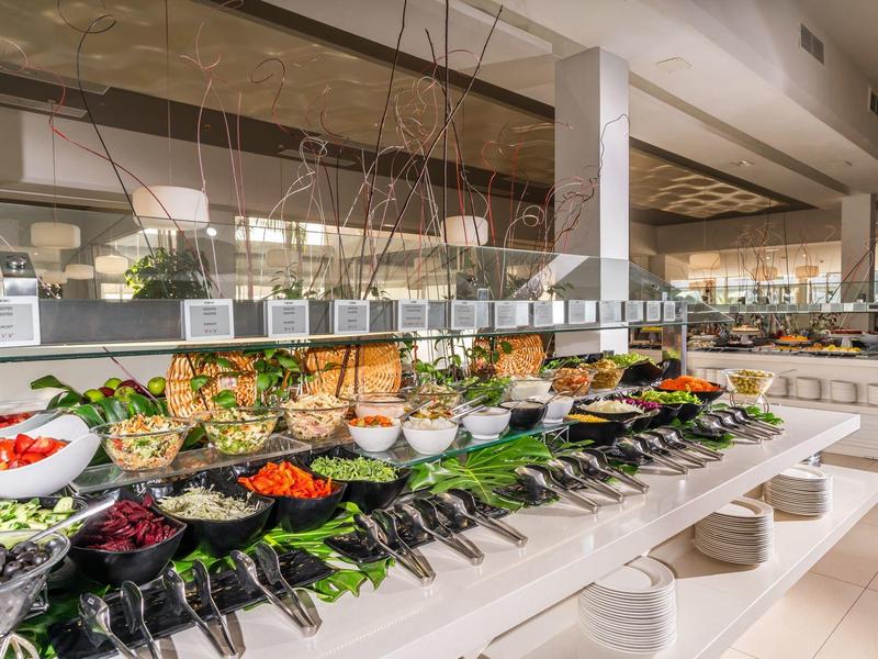 Buffet mit frischem Salat und Gemüse in einem hellen Hotelrestaurant.