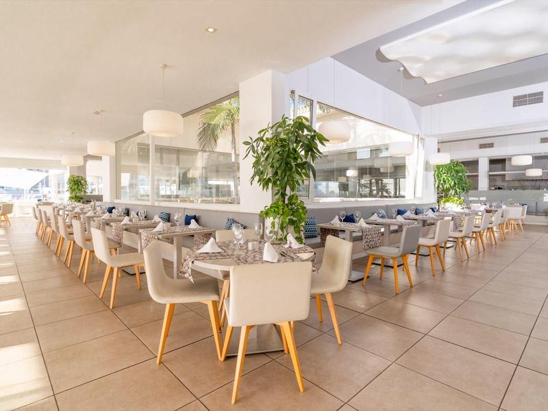 Modernes, helles Restaurant mit gedeckten Tischen und bequemen Stühlen in warmem Licht.