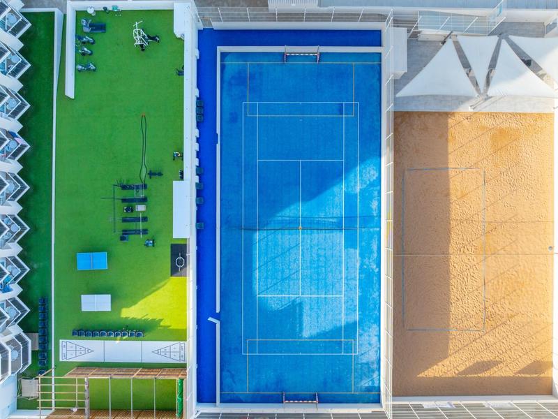 Drei unterschiedliche Sport- und Freizeitbereiche neben einem modernen Gebäude von oben gezeigt.