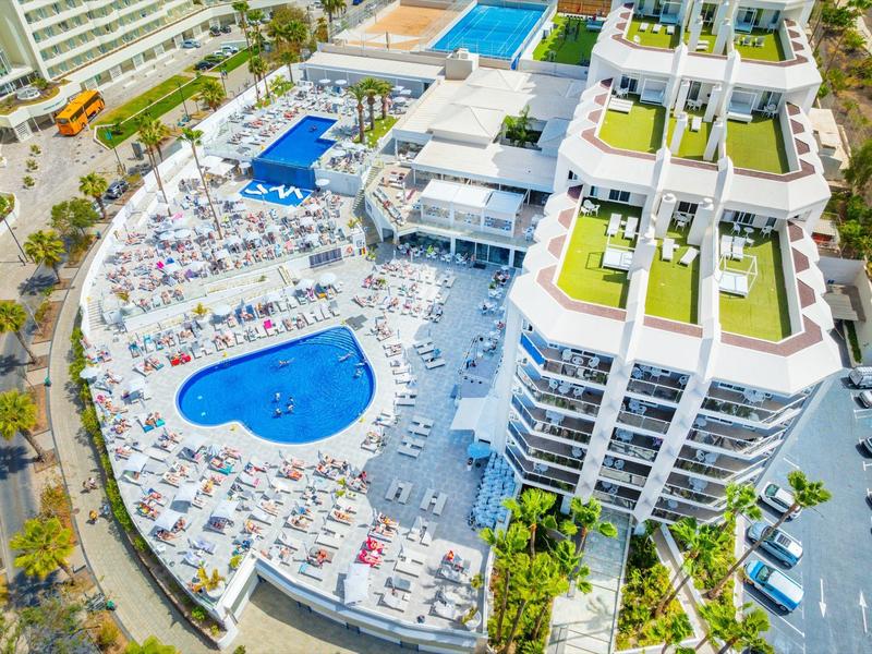 Luftaufnahme eines Hotels mit Pool, Liegestühlen und begrünten Dächern.