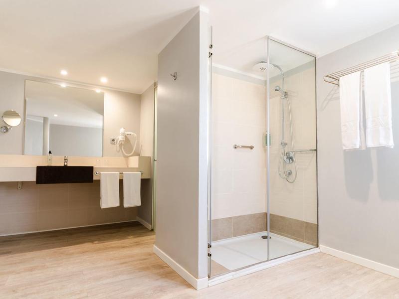 Modernes Badezimmer mit Glasdusche, großem Spiegel und minimalistischem Design.