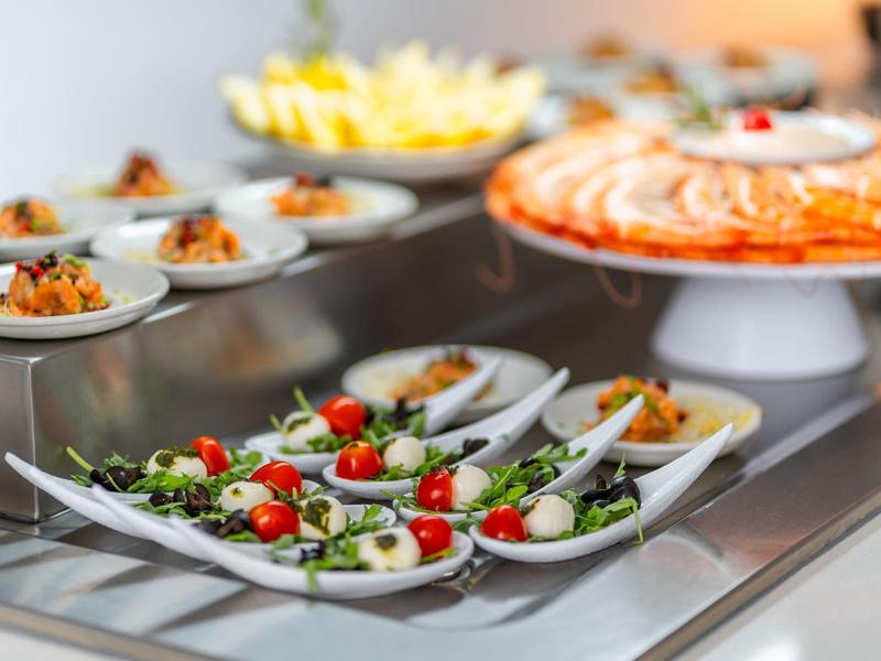 Verschiedene Vorspeisen auf weißen Tellern auf einem Buffet mit Salaten und Meeresfrüchten.