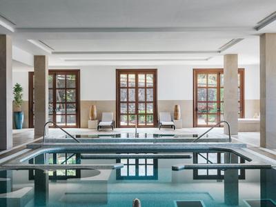 Widok wnętrza nowoczesnego jacuzzi w jasnej strefie wellness z oknami i miejscami do siedzenia.