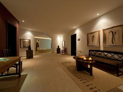 Jasno oświetlony korytarz hotelowy z ławkami, dekoracyjną sztuką i dywanami.