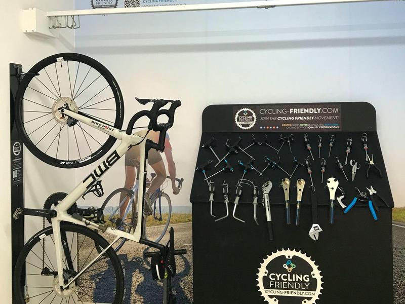 Rower zamontowany na ścianie obok stojaka z narzędziami do napraw rowerów.