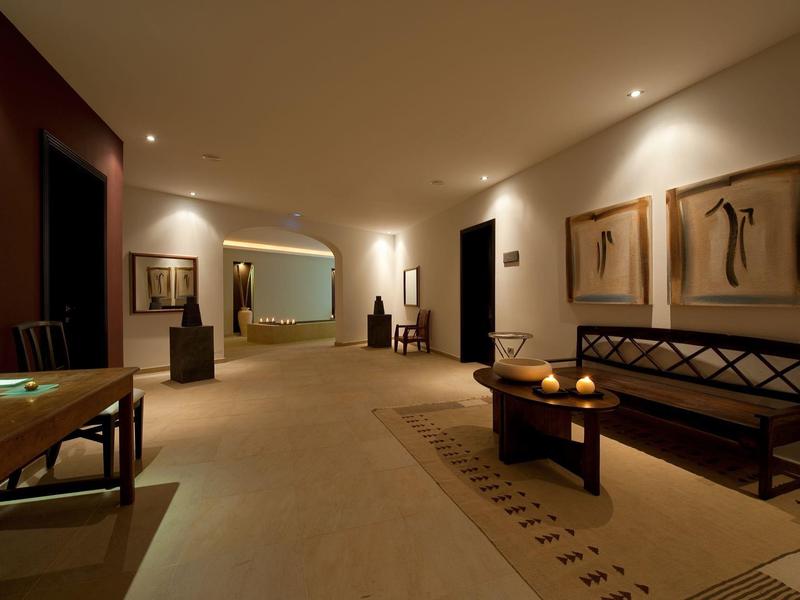 Jasno oświetlony korytarz hotelowy z ławkami, dekoracyjną sztuką i dywanami.