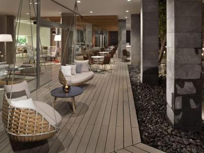 Moderner, gemütlicher Außenbereich mit Hängestühlen und Holzterrasse neben Steinsäulen.