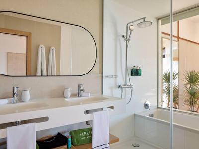 Salle de bain moderne avec double lavabo, grand miroir et douche vitrée.