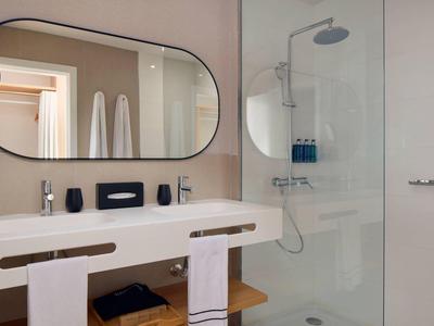 Salle de bain moderne avec grande vasque, miroir ovale et douche vitrée.