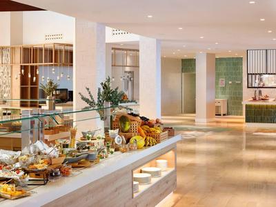 Buffet de petit-déjeuner moderne avec fruits frais et pâtisseries dans un espace lumineux.