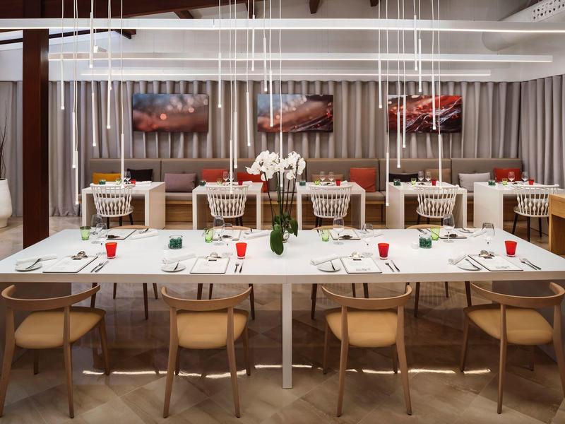 Salle à manger moderne avec grande table blanche et chaises en bois clair.