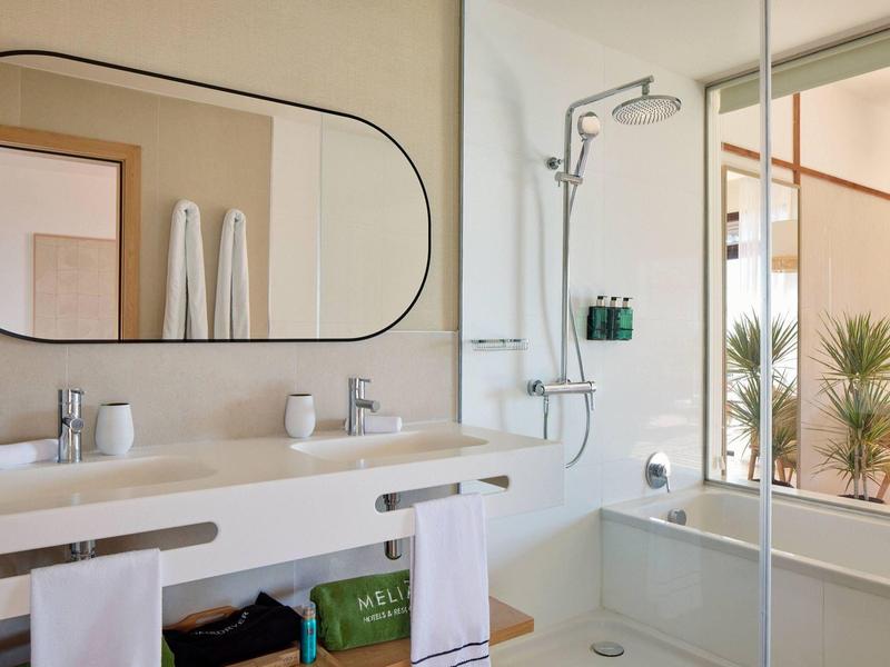 Salle de bain moderne avec double lavabo, grand miroir et douche vitrée.