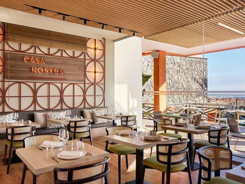 Bar et restaurant élégants avec vue sur mer dans un hôtel lumineux.