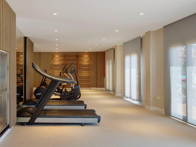 Salle de sport moderne avec tapis de course et murs en bois clair.