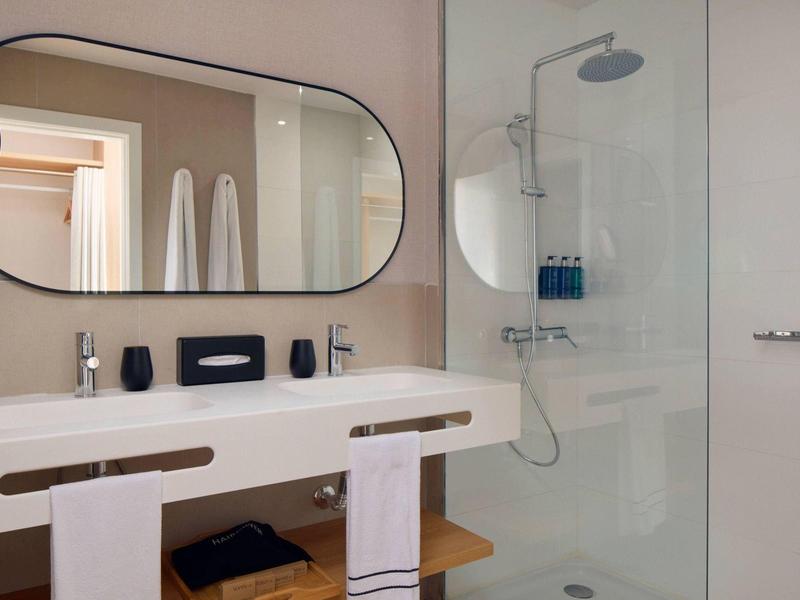 Salle de bain moderne avec grande vasque, miroir ovale et douche vitrée.
