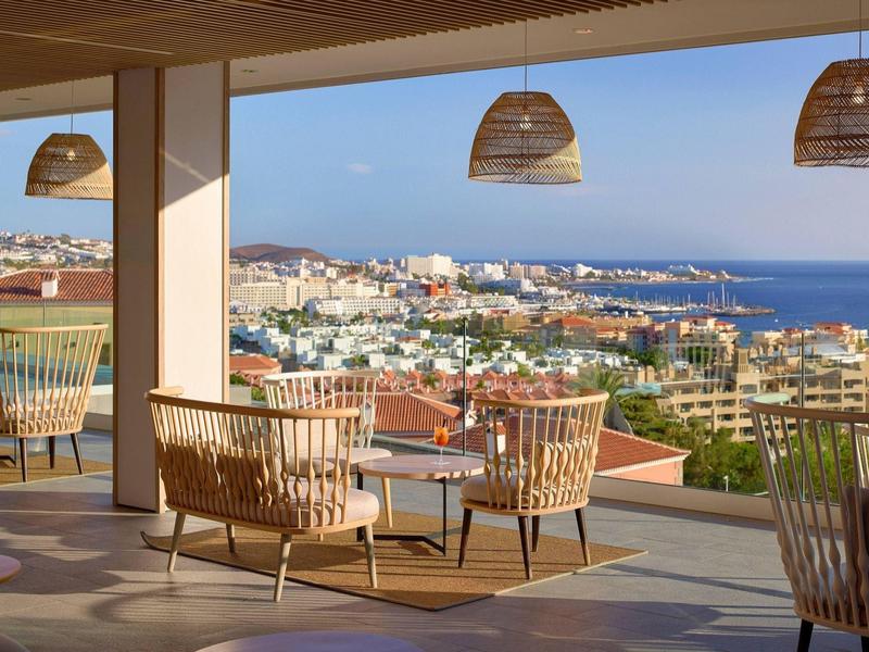 Terrasse d'un hôtel avec vue sur la mer et la ville sous un ciel clair.