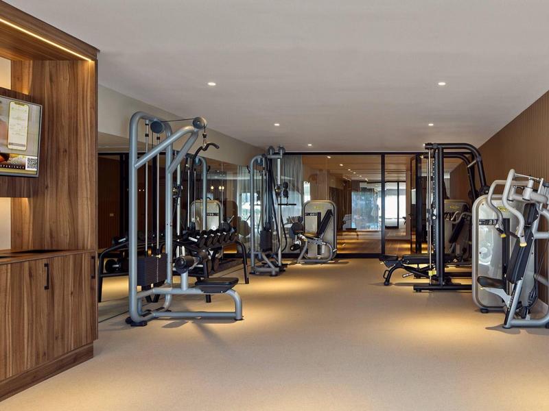 Salle de sport moderne avec équipement complet et décoration en bois et beige.