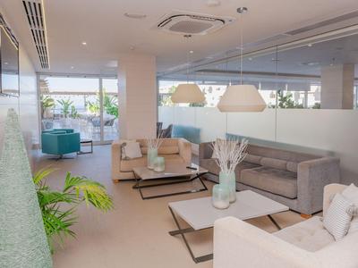 Jasny salon z nowoczesnymi sofami, stołami i roślinami w części hotelowej.