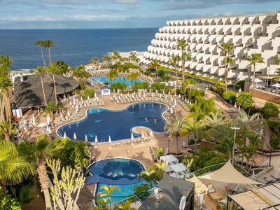 Kompleks hotelowy z basenem, tarasem słonecznym i widokiem na morze w słoneczny dzień