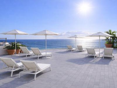 Puste leżaki i parasole na tarasie z widokiem na morze pod słonecznym niebem.