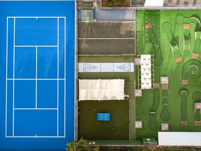 Widok z góry na kort tenisowy i pole do minigolfa obok siebie w hotelowym ogrodzie.