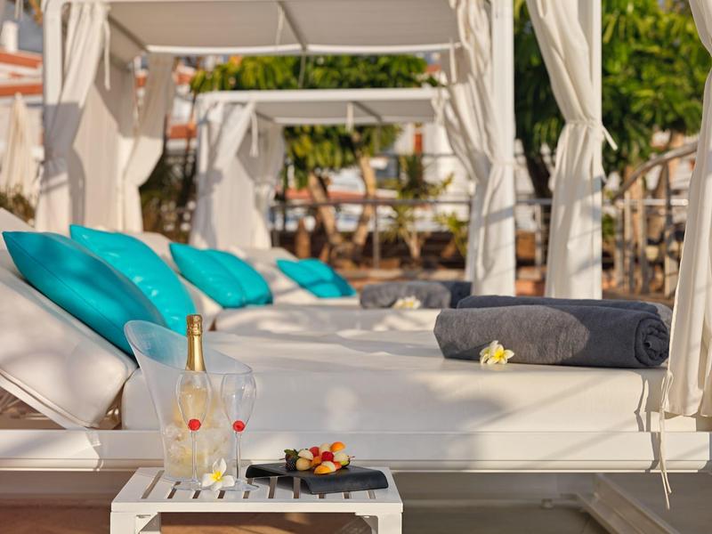 Luxury sunbeds with turquoise cushions and drinks in a sunny outdoor setting.