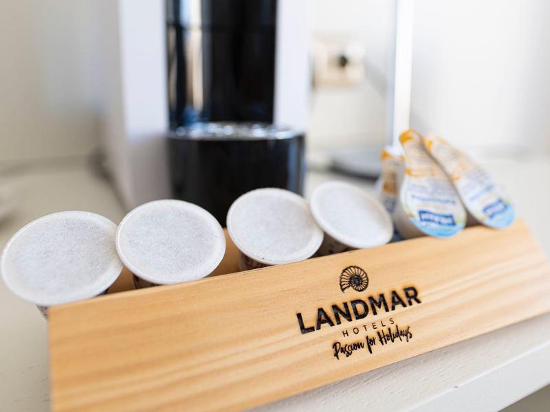 Coffee capsules and milk sticks on a wooden tray with hotel branding.
