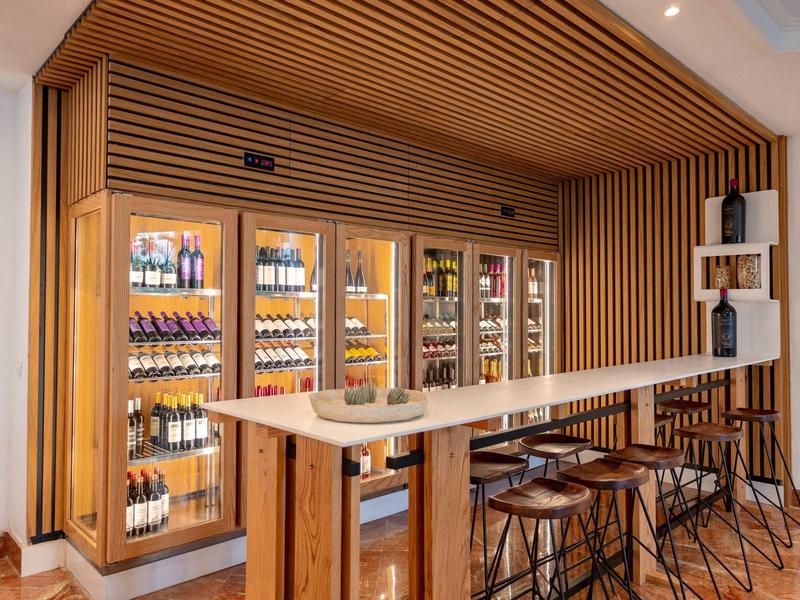 Modern hotel bar with wooden paneling, high stools, and well-stocked drink shelves.
