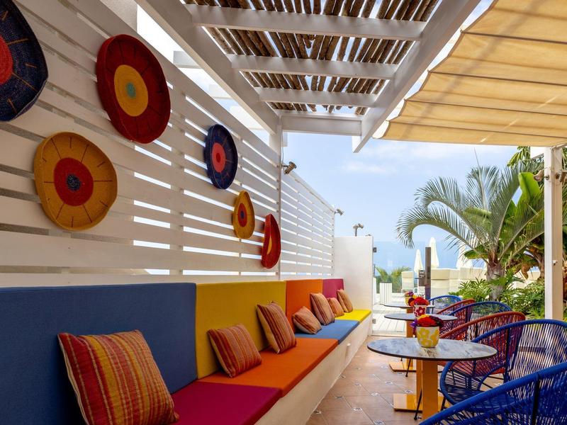 Cozy lounge with colorful cushions and decorations in an outdoor hotel area.